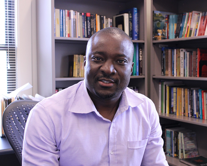 Desmond Odugu in front of bookshelves